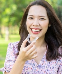 Woman pointing to a straight smile using Invisalign in Richmond.
