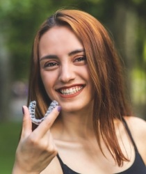 Hand holding pair of clear aligners.