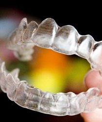 Hand holding pair of clear aligners.