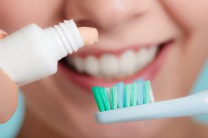 woman applying toothpaste to toothbrush