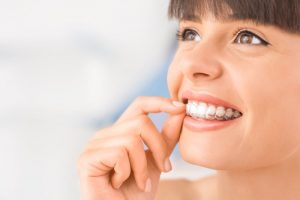 attractive young woman smiling inserting Invisalign in richmond